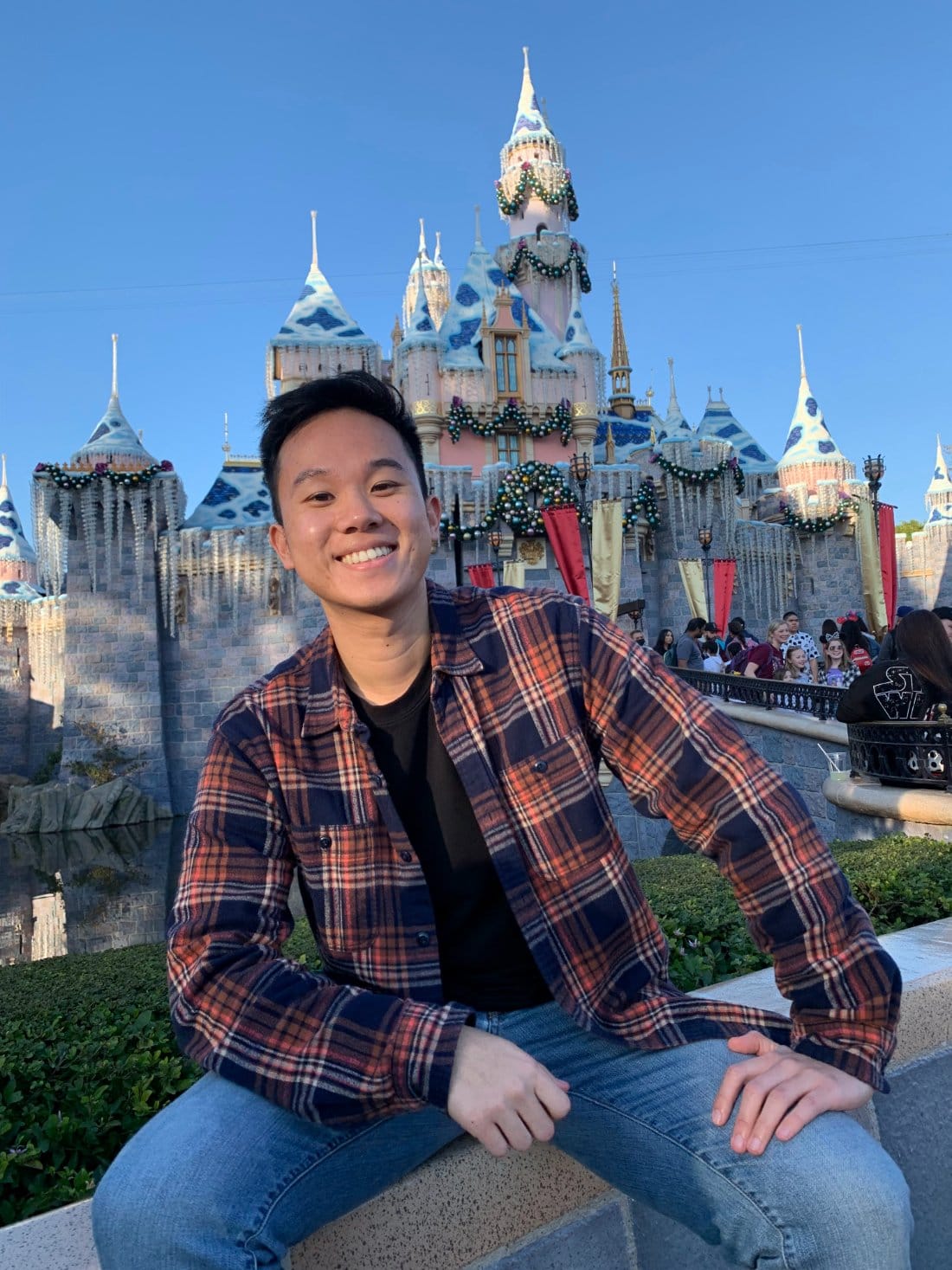 Andrew Lin smiling in front of the Disneyland castle